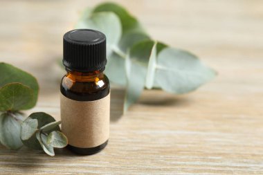 Okaliptüs, ahşap zemin üzerinde yeşil okaliptüs yaprakları olan cam bir şişede gerekli yağdır. Aromaterapi konsepti. Spa mı? Kozmetik ve vücut bakımı için doğal organik malzemeler.