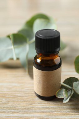 Okaliptüs, ahşap zemin üzerinde yeşil okaliptüs yaprakları olan cam bir şişede gerekli yağdır. Aromaterapi konsepti. Spa mı? Kozmetik ve vücut bakımı için doğal organik malzemeler.