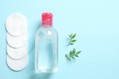 Micellar 'ın temizleme suyu ve pamuk pedleri. Renkli arka plan, üst manzara. Düz yatıyordu.