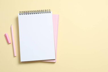 Renk arkaplanında kalem bulunan defterler, üst görünüm