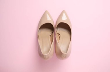 Pembe arka planda klasik kadın bej topuklu ayakkabıları. Üst manzara, düz yatış. Ayakkabı satışı, reklam tasarımı konsepti.