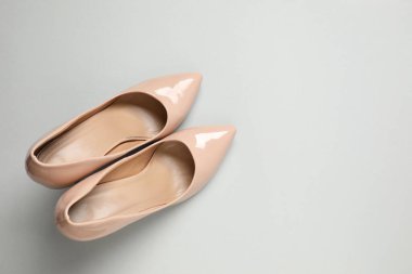 Gri arka planda klasik kadın bej topuklu ayakkabıları. Üst manzara, düz yatış. Ayakkabı satışı, reklam tasarımı konsepti.