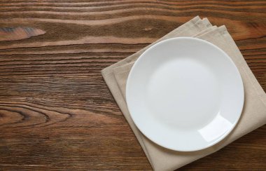 Tahta arka planda boş yuvarlak tabak, üst görünüm