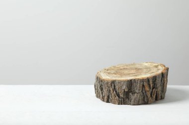 Tahta beyaz bir masanın üzerinde duruyor. Ürün sunumu için ağaç gövdesi kesilmiş. Ön görünüm