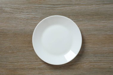 Tahta arka planda boş yuvarlak tabak, üst görünüm