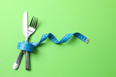 Renk arkaplanında çatal bıçak takımı olan mavi mezura, üst görünüm.