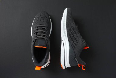 Siyah arka planda şık bir çift spor ayakkabı.