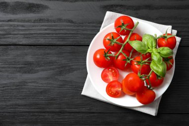 Bir demet taze kırmızı domates ve ahşap arka planda fesleğen.