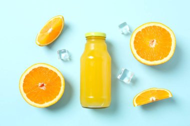 Bir şişe taze sıkılmış portakal suyu. Arka planda turunçgiller var.
