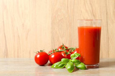 Bardakta domates suyu ve masada taze domates.