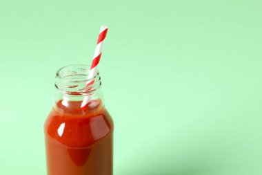 Cam şişede domates suyu ve arka planda taze domates.