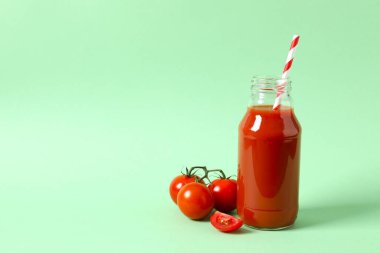 Cam şişede domates suyu ve arka planda taze domates.