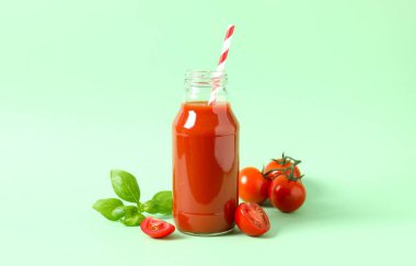 Cam şişede domates suyu ve arka planda taze domates.