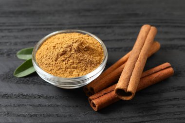 Tarçın çubukları ve tarçın tozu ahşap bir arka planda bir tabakta