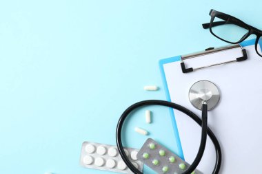 Renk arkaplanında haplı steteskop ve pano, üst görünüm