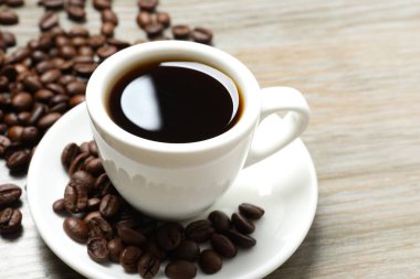 Bir fincan kahve ve kahve çekirdeği ahşap masada.