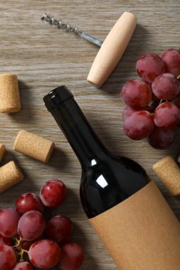 Ahşap arka planda üzüm ve mantarlı bir şişe kırmızı şarap.