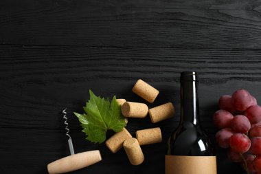 Üzümlü bir şişe kırmızı şarap, ahşap arka planda tirbuşon ve mantar.