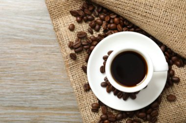 Ahşap arka planda bir fincan kahve ve fasulye.