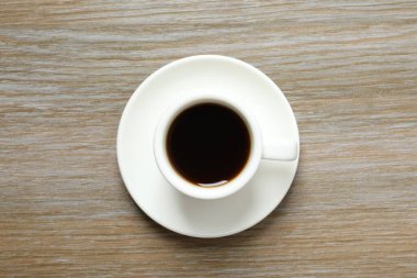 Ahşap arka planda bir fincan kahve ve fasulye.