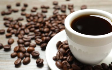 Ahşap arka planda bir fincan kahve ve fasulye.