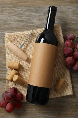 Ahşap arka planda üzüm ve mantarlı bir şişe kırmızı şarap.