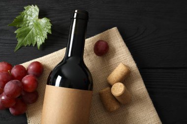 Ahşap arka planda üzüm ve mantarlı bir şişe kırmızı şarap.