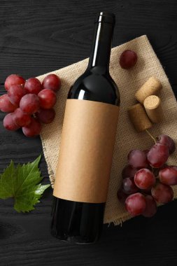 Ahşap arka planda üzüm ve mantarlı bir şişe kırmızı şarap.