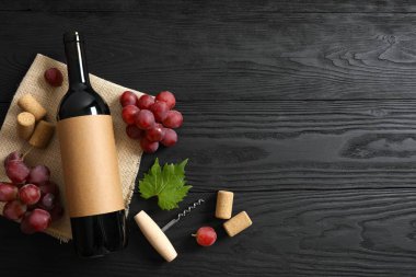 Ahşap arka planda üzüm ve mantarlı bir şişe kırmızı şarap.