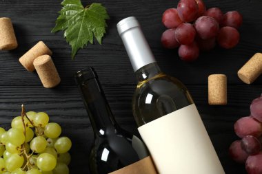 Ahşap arka planda üzüm ve mantarlı bir şişe kırmızı ve beyaz şarap.