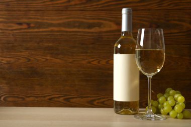 Üzümlü bir şişe beyaz şarap ve ahşap zemin üzerinde cam.