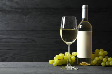 Üzümlü bir şişe beyaz şarap ve ahşap zemin üzerinde cam.