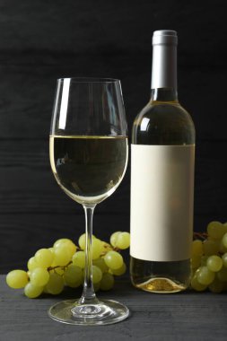 Üzümlü bir şişe beyaz şarap ve ahşap zemin üzerinde cam.