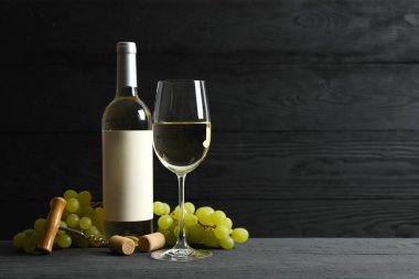 Üzümlü bir şişe beyaz şarap ve ahşap zemin üzerinde cam.