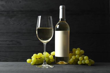 Üzümlü bir şişe beyaz şarap ve ahşap zemin üzerinde cam.