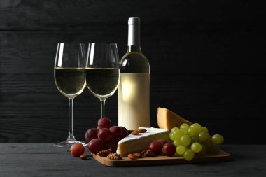 Tahta bir masada çeşitli peynirler, üzümler, fındıklar ve beyaz şarap