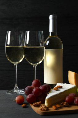 Tahta bir masada çeşitli peynirler, üzümler, fındıklar ve beyaz şarap