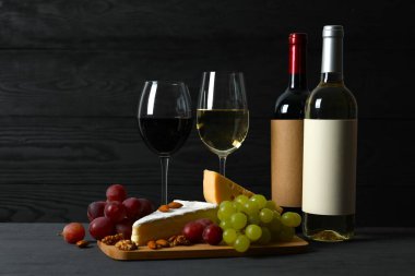 Tahta bir arka planda çeşitli peynirler, üzümler, fındıklar ve şarap