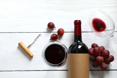 Üzümlü kırmızı şarap, tirbuşon ve ahşap arka planda gözlük.