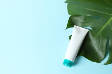 Renkli arka planda canavar yaprağı olan kozmetik tüpü.