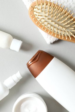 Kişisel bakım ürünleri ve gri arka planda ahşap tarak 