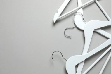 Ahşap elbiseler gri arka planda asılı.