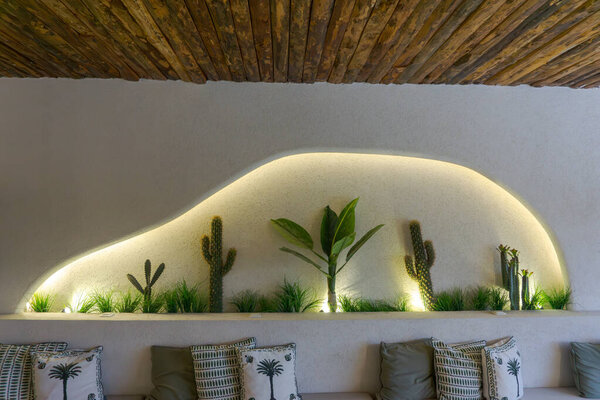 Стильный декор, кактусы и растительный акцент живая стена ниша. Изогнутая, уникальная настенная ниша со встроенным диваном с подушками. Современный сельский интерьер. Идея деревянного потолка