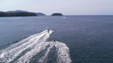 Su motosikletlerinin, sürat teknelerinin, Tayland ve Karon sahillerinin hava görüntüleri. Phuket Adası 'nda yaşam, su motosikleti aktiviteleri, spor, su üzerinde insansız hava aracı saldırısı, dalgalar, Karon plajı. Yüksek kalite 4k