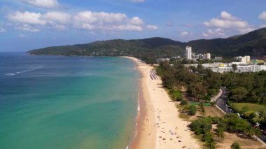 Karon sahili, Phuket sahil şeridi, ağaçlar, kum, turkuaz su. Kıyıdaki ağaçlardan bir drone uçurmak doğrudan suya, turkuaz temiz su, sürat tekneleri, güneşlenen insanlar