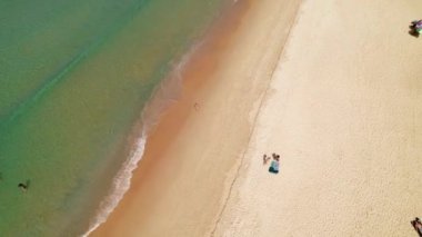 Hava manzaralı, Karon sahilinde koşan bir adam, turkuaz su, kıyı şeridi, insansız hava aracı. Sahil aktivitesi, Phuket Tayland 'da yaşam, kumsalda uçmak, İHA' dan en iyi görüntü. güneş banyosu ve yüzen insanlar