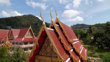 Wat karon tapınağının çatılarında uçmak, üst görüş, inanç, Budizm, manzara. Güzel mimari binalar, gelenekler ve Tayland kültürü, hava manzarası, altın süsler ve heykeller. Yüksek