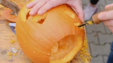 Cadılar Bayramı için balkabağı hazırlıyorum. Yetişkin birinin elleri balkabağıyla korkunç bir şekil oyuyor. Cadılar Bayramı dekorasyonu.