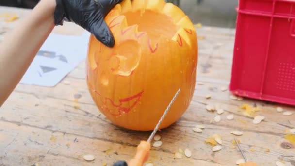 Przygotowuję Dynię Halloween Ręce Dzieciaka Czarnych Rękawiczkach Rzeźbią Przerażającą Postać — Wideo stockowe