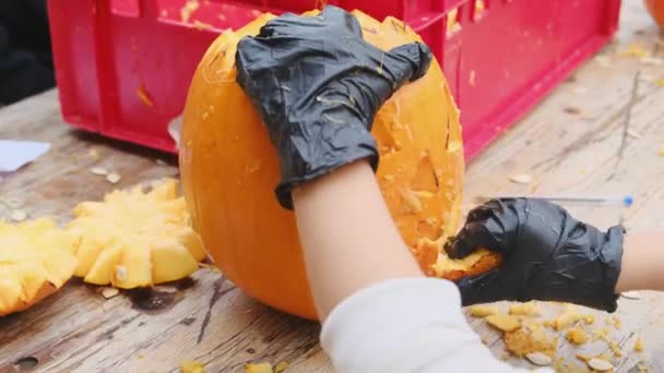 ハロウィーンのためのカボチャの準備 黒い手袋の子供の手はカボチャで怖い姿を彫ります ハロウィーンの装飾 — ストック動画